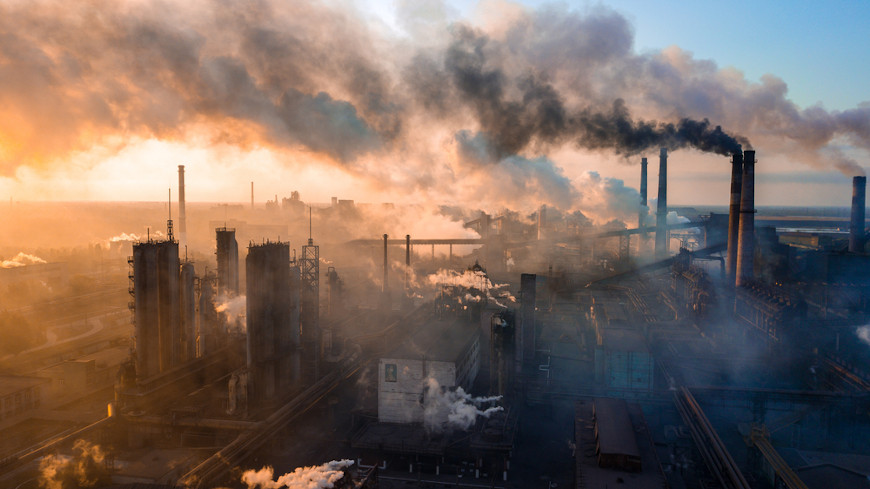 Região industrial liberando gases poluentes como representação de como a ação humana influencia a chuva ácida.