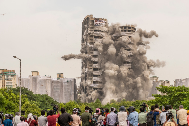  Pessoas observando a demoliÃ§Ã£o de duas torres que foi feita em 9 segundos, com 3700 kg de dinamite, na Ãndia, em 2022.
