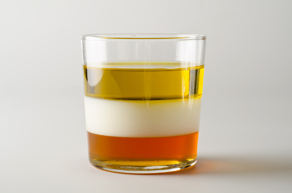 Copo com óleo vegetal, leite e mel, em diferentes posições, como representação da densidade.