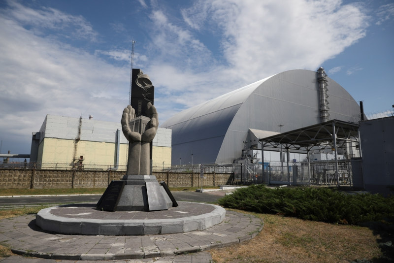 Monumento às vítimas do acidente de Chernobyl em frente ao Novo Confinamento Seguro, na zona de exclusão.