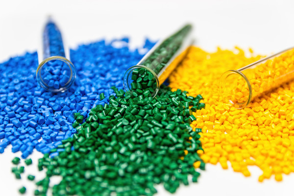 Pequenas partículas de plástico, um dos polímeros mais conhecidos, nas cores azul, verde e amarela esparramadas.