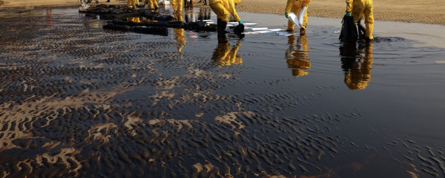 Limpeza do litoral oceânico após um vazamento de petróleo, um dos impactos dos combustíveis fósseis.