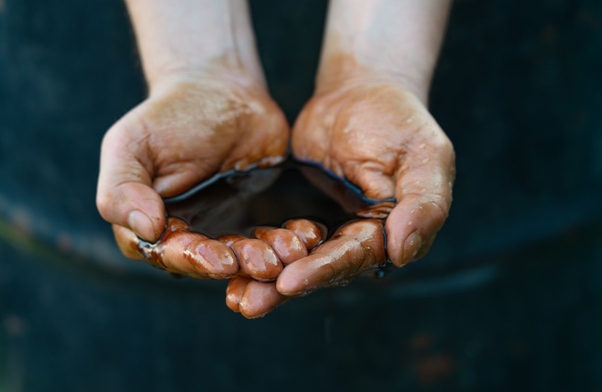 Homem trabalhando junto a uma m&aacute;quina de colocar asfalto, produto feito de alcanos.