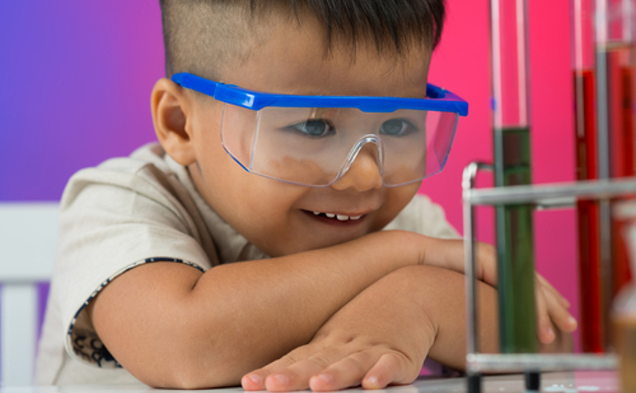 Garoto observando uma curiosidade de Química em experimento